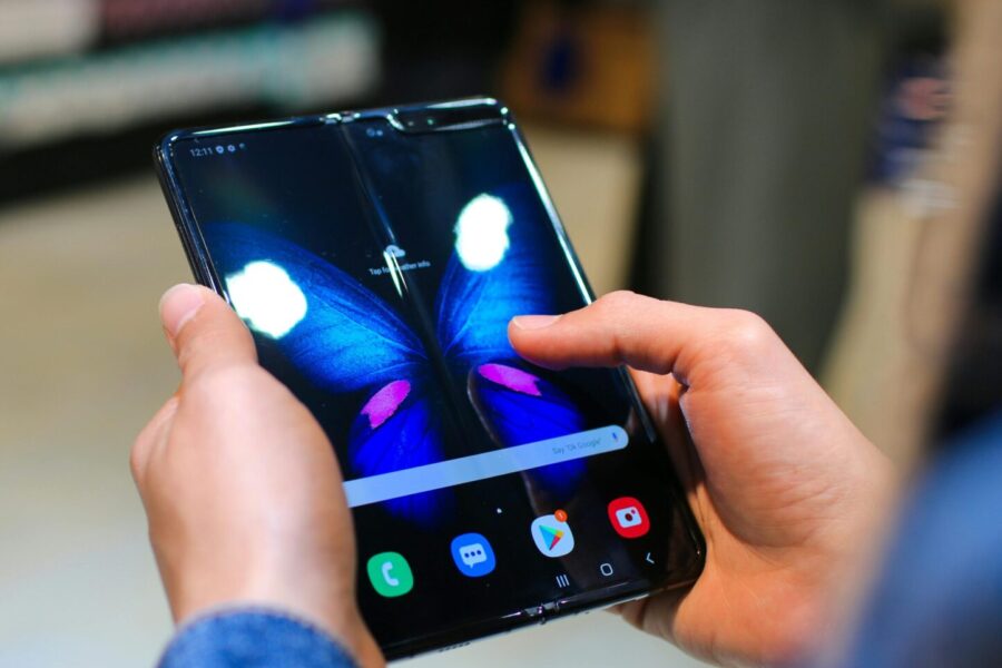 Close-up of hands holding a foldable smartphone showing a butterfly on the screen.