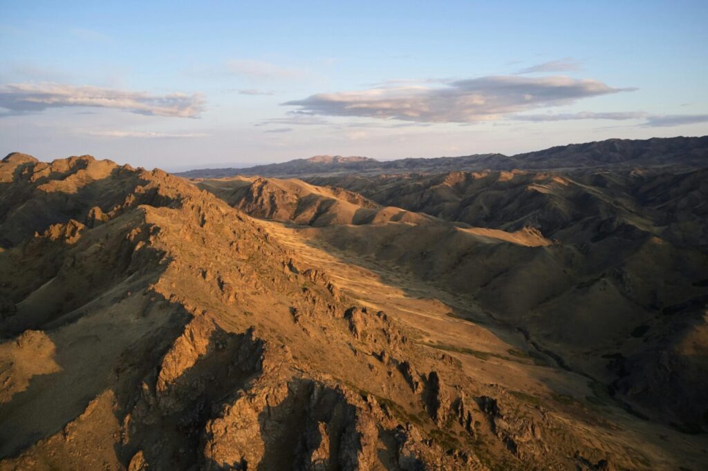 Picturesque wild mountain range slowly becoming dark under evening sky with rare clouds at sundown