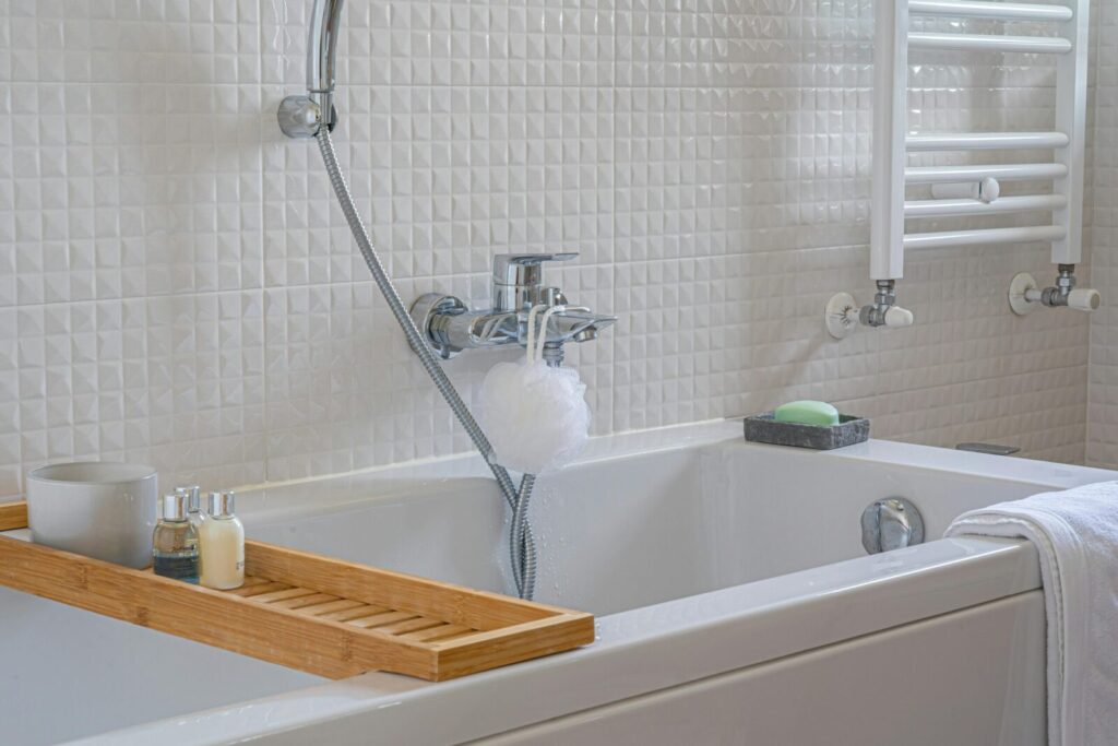 A modern bathroom with a wooden tray holding bath essentials, perfect for relaxation.