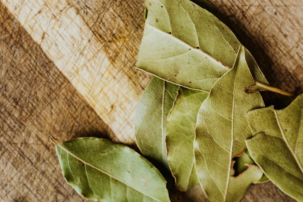 Flat lay of bay leaves on a rustic wooden cutting board, perfect for culinary use.