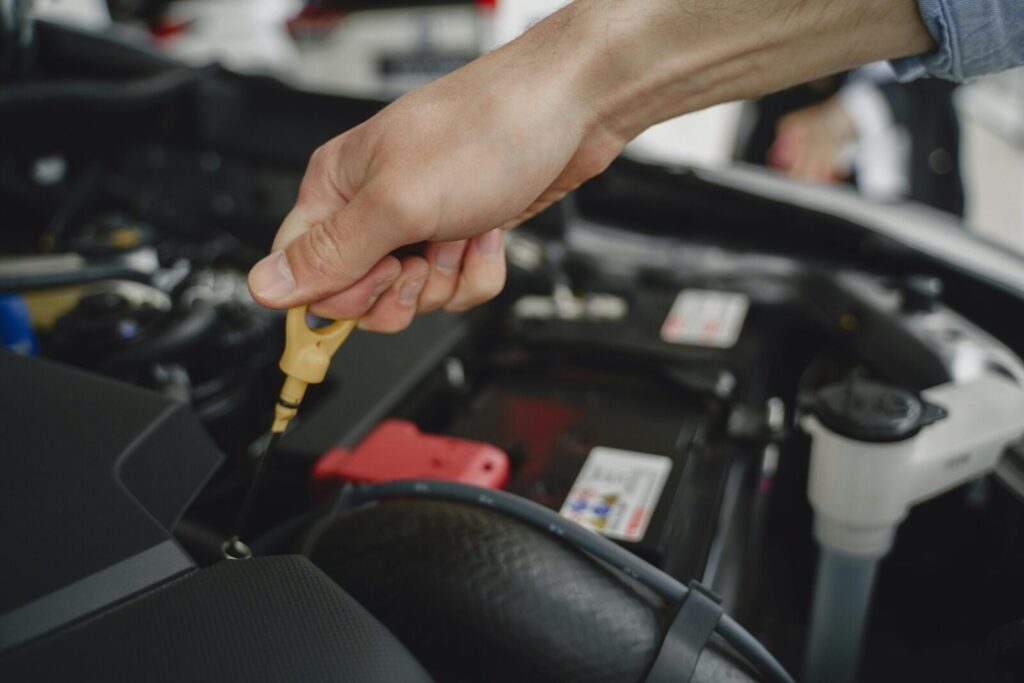 Hand checking oil dipstick in a car engine bay for maintenance and diagnostics.