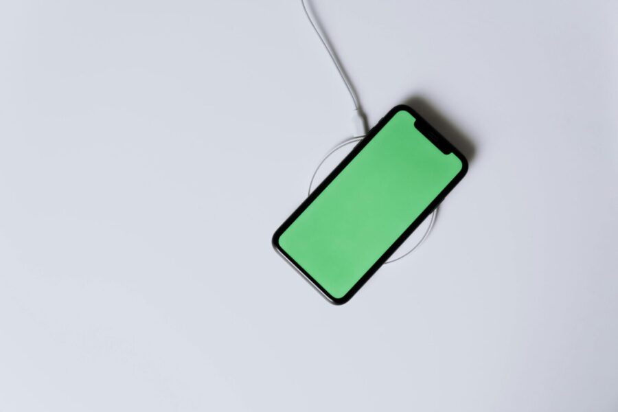 Overhead view of a smartphone with a green screen on a wireless charger, showcasing modern technology.