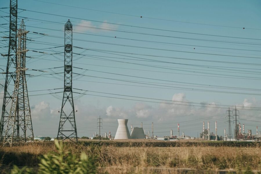 Scenic view of high voltage towers and power plant against a clear sky over dry grassland.