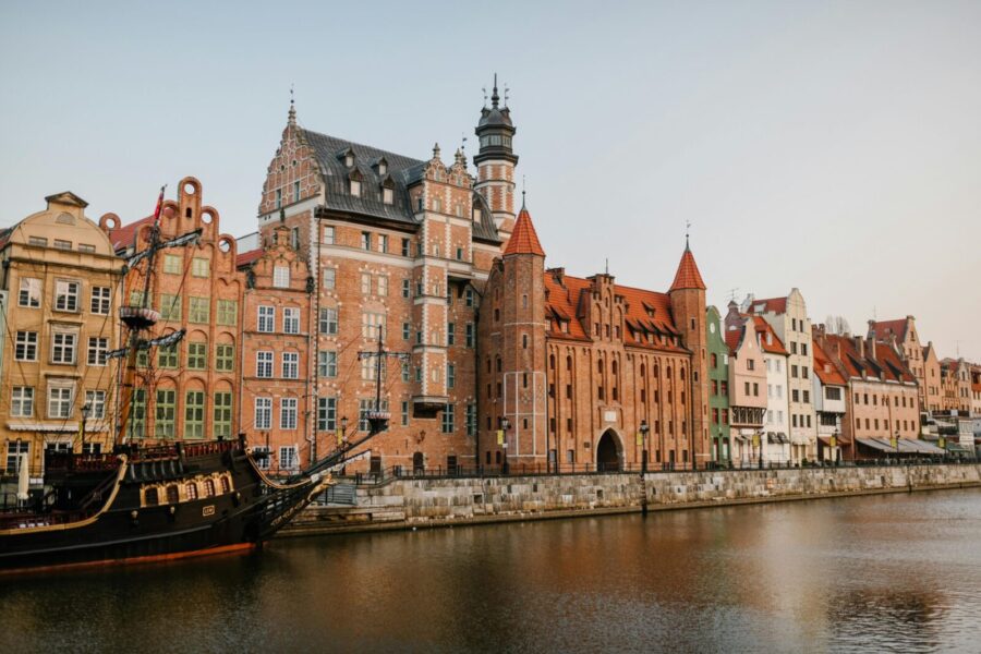 Exterior of historic residential buildings located on calm canal shore in Gdansk Poland on clear day