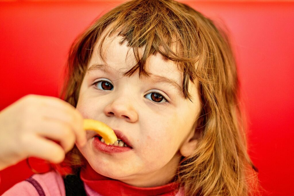 Close-up of a child eating french fries, showcasing an adorable and candid moment.