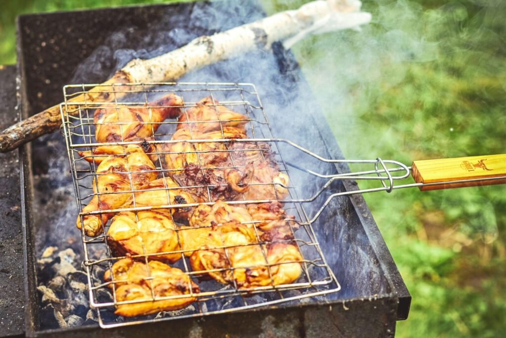 Close-up of grilled chicken on an outdoor barbecue, emitting smoke and flavor.
