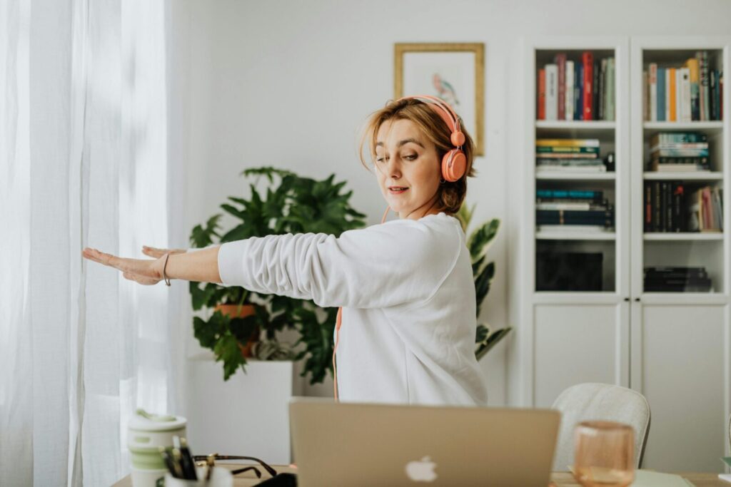 Woman exercising with headphones in a cozy home office setting. Lifestyle and wellness focus.