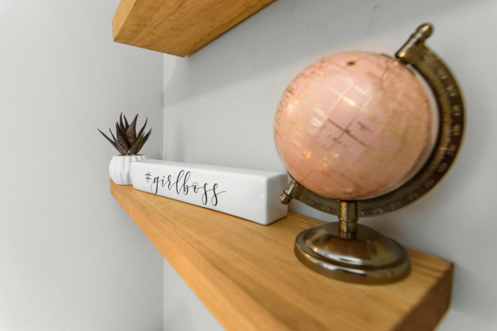 Close-up of a stylish shelf featuring a pink globe and #girlboss decor for modern workspace inspiration.