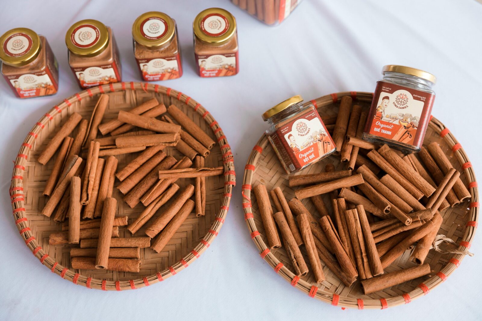 Organic cinnamon sticks arranged in woven trays alongside cinnamon jars, ideal for product packaging.