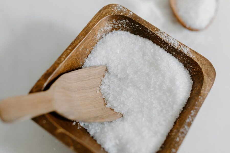 Close-up of coarse sea salt in a wooden bowl with a wooden scoop, perfect for culinary use.