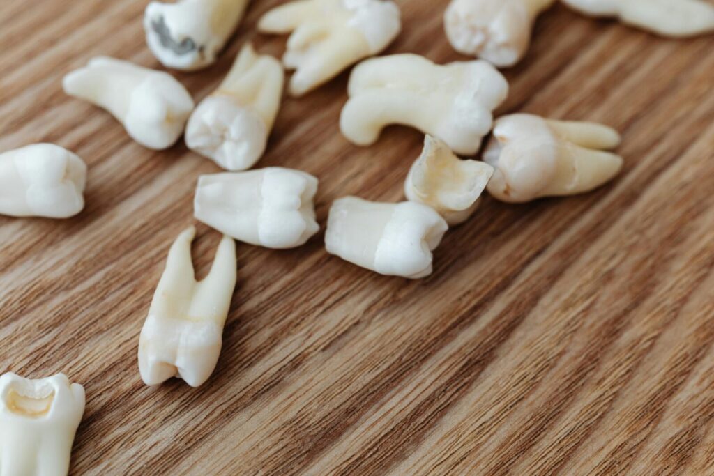 A detailed close-up of multiple extracted human teeth arranged on a wooden background surface.