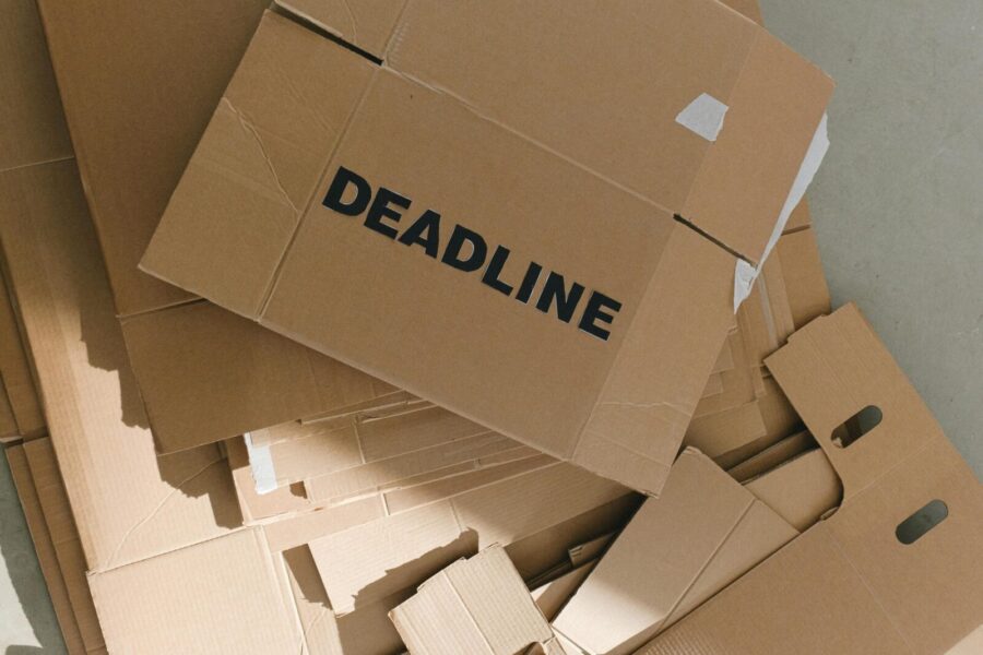 Pile of cardboard boxes with bold 'Deadline' label indoors, emphasizing urgency.