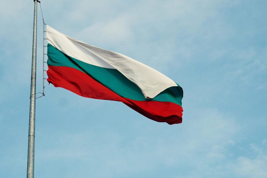 The national flag of Bulgaria waving on a flagpole against a clear blue sky in Varna.