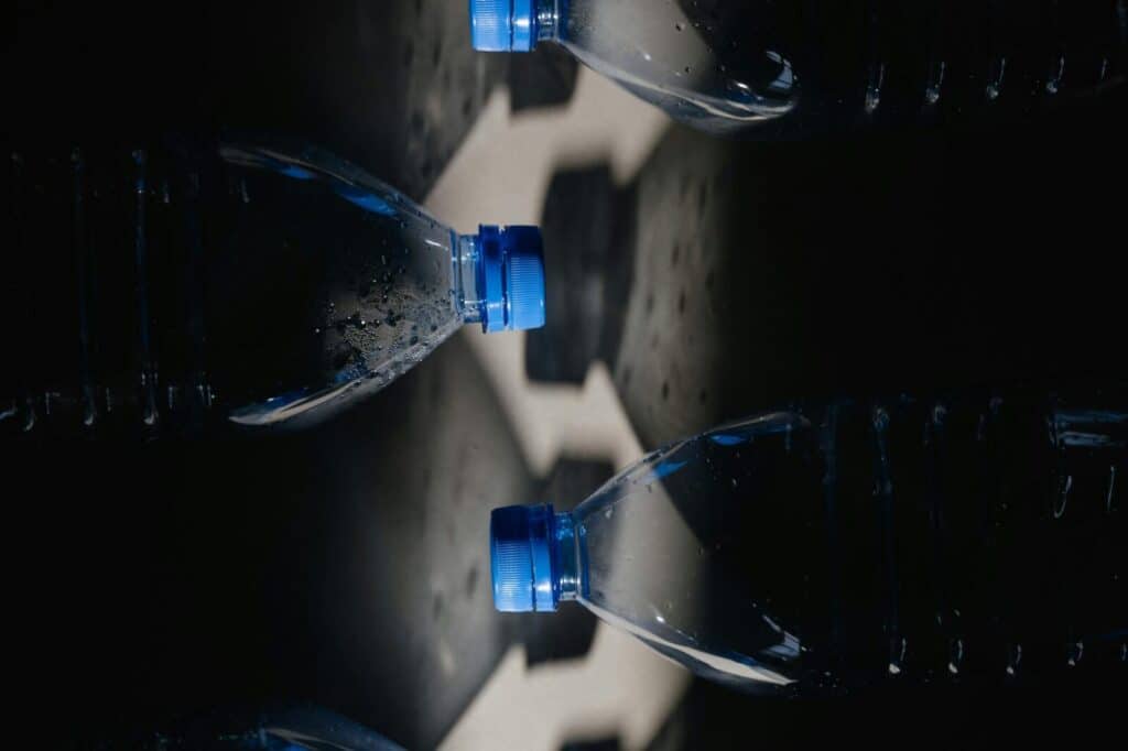 Creative close-up of plastic bottles with reflection highlighting water pollution.