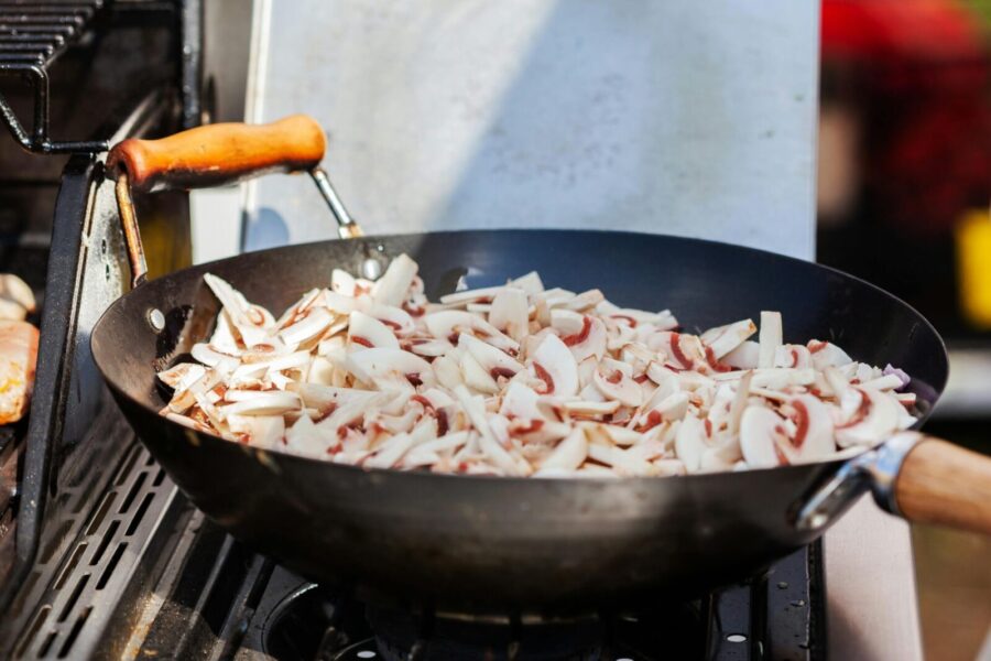 Close-up view of sliced mushrooms cooking in a wok outdoors. Perfect for culinary themes.