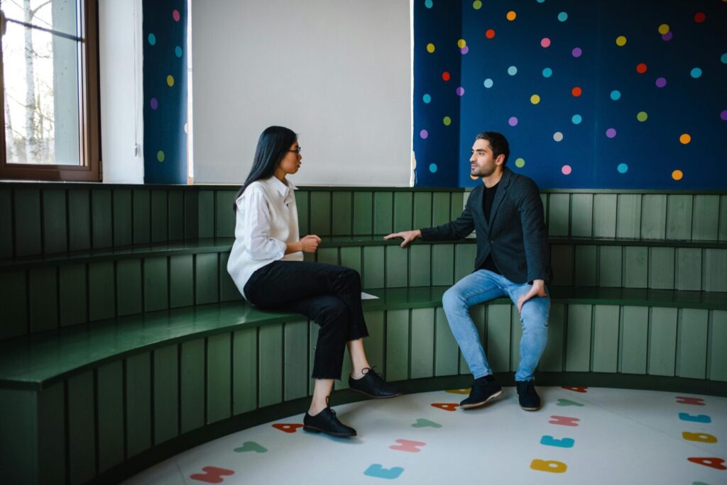 Two young professionals having a conversation in a colorful, modern, indoor space.