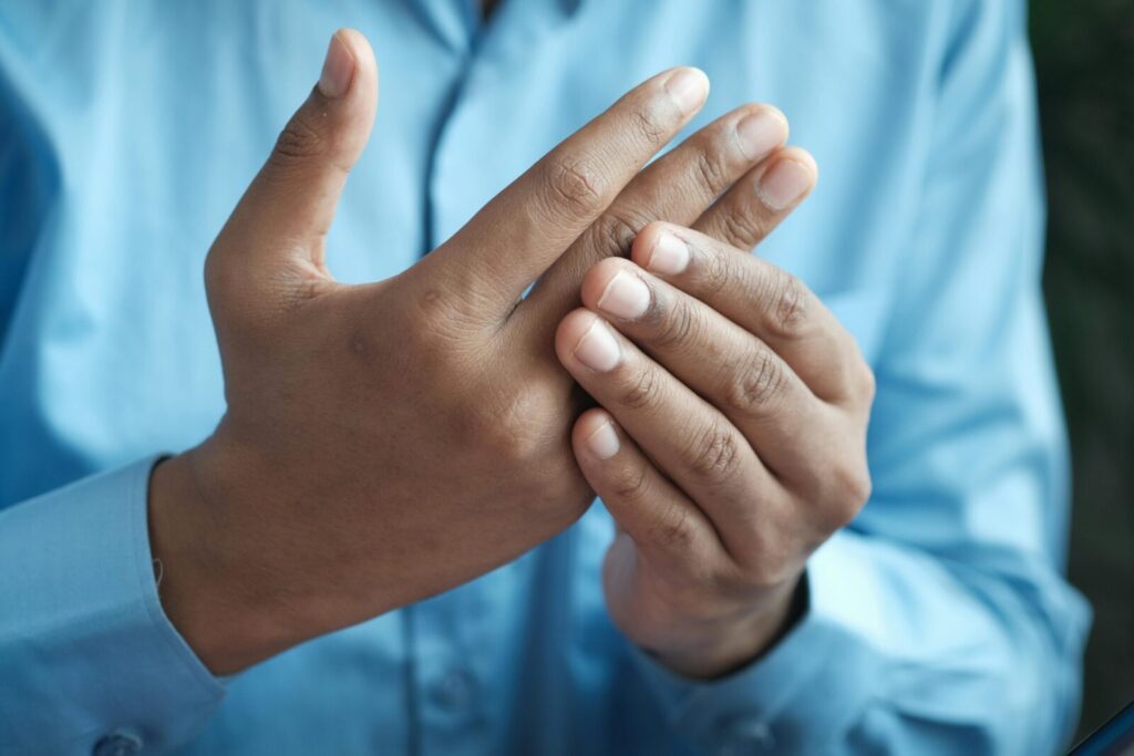 Close-up of a man gently holding his hand, symbolizing comfort or pain relief.