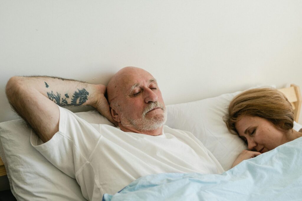 Peaceful elderly couple sleeping together in bed, showing relaxation and comfort.