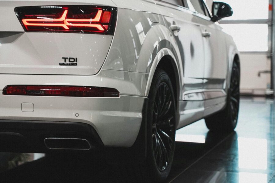Detailed view of a luxury white car's rear end and taillight in a garage setting, showcasing modern design.