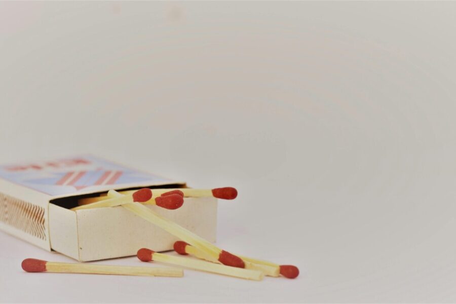 A close-up of an open matchbox with scattered matches on a white surface. Ideal for safety themes.