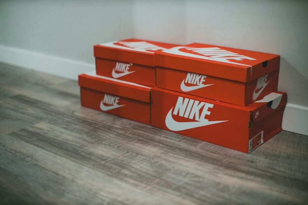 Red Nike shoe boxes stacked neatly on a wooden floor indoors.