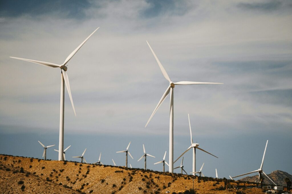 A large wind farm with turbines on a desert hill under a clear sky.