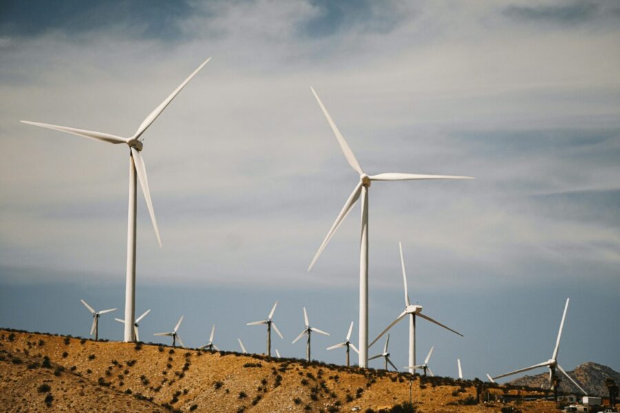 A large wind farm with turbines on a desert hill under a clear sky.
