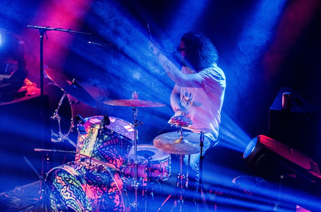 A man is playing drums on stage at a concert