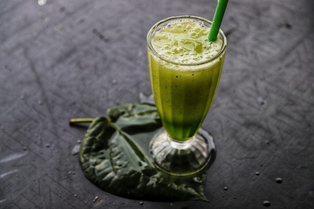 a green smoothie with a green straw in a tall glass
