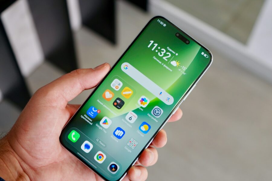 Hand holding a modern smartphone with a green interface.