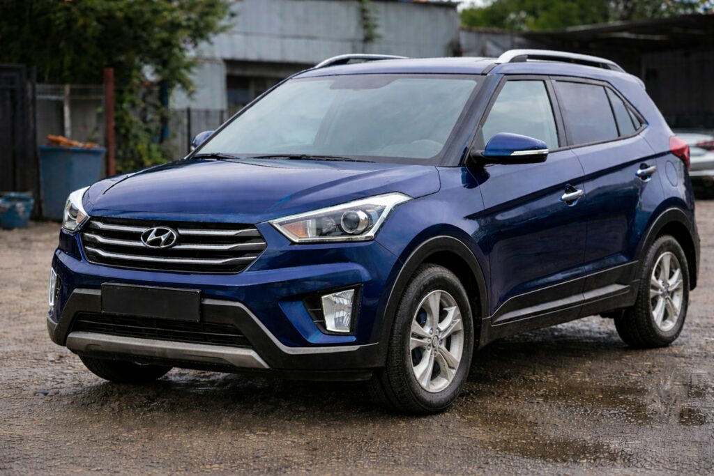 A blue hyundai suv parked on a wet street.