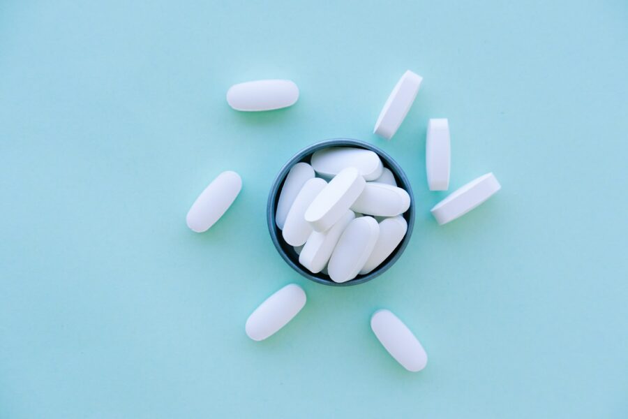 A bowl of pills on a blue surface