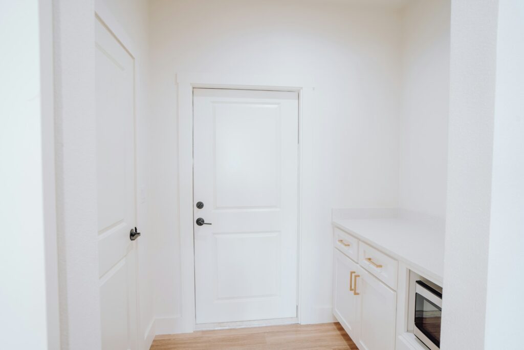 a kitchen with a white door and white cabinets