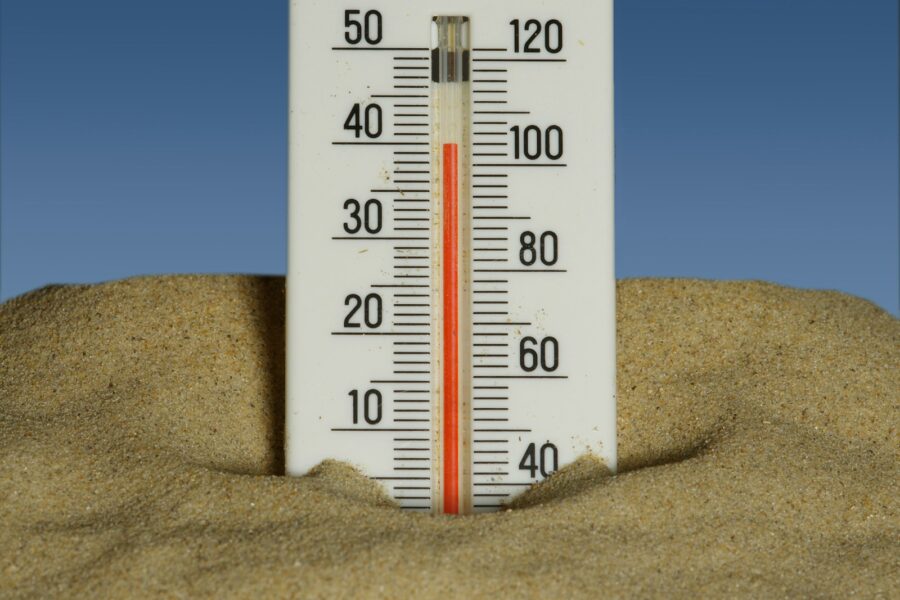 A thermometer in the sand with a blue sky in the background