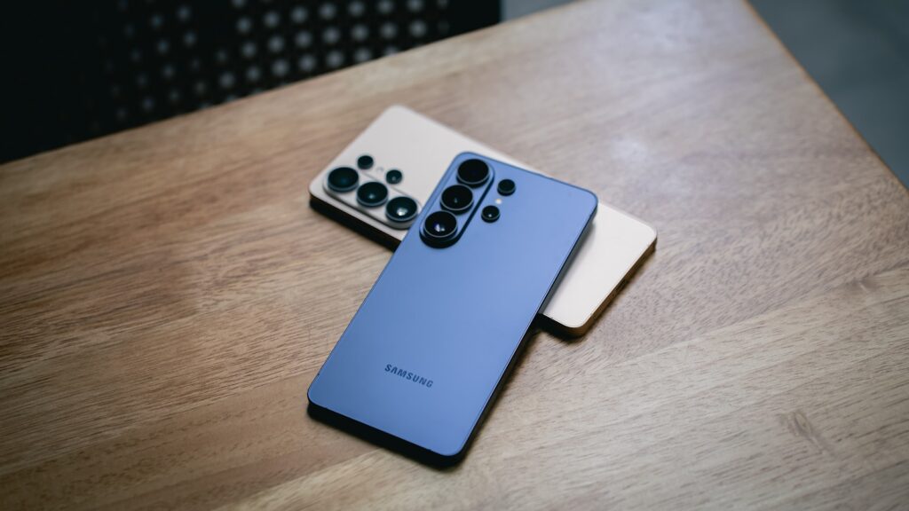 Two modern smartphones with multiple cameras on wooden surface