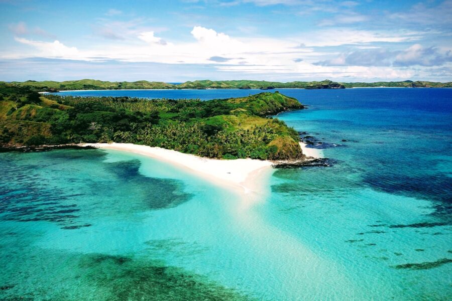 a beach with blue water and green land