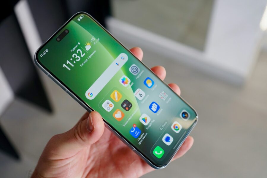 Hand holding a modern smartphone with colorful app icons.