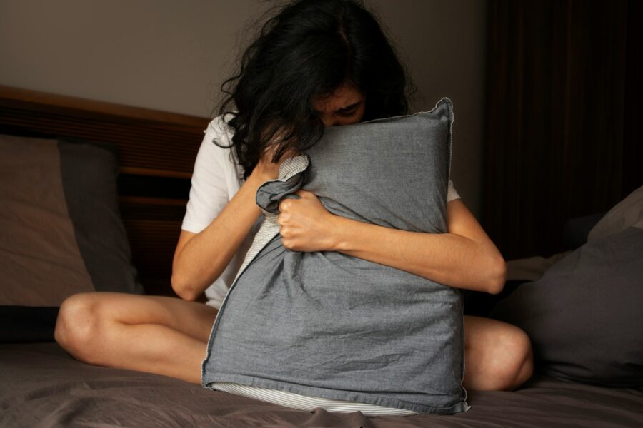 A woman sitting on a bed holding a pillow