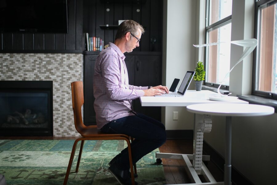 man in gray dress shirt sitting on brown wooden chair using macbook pro