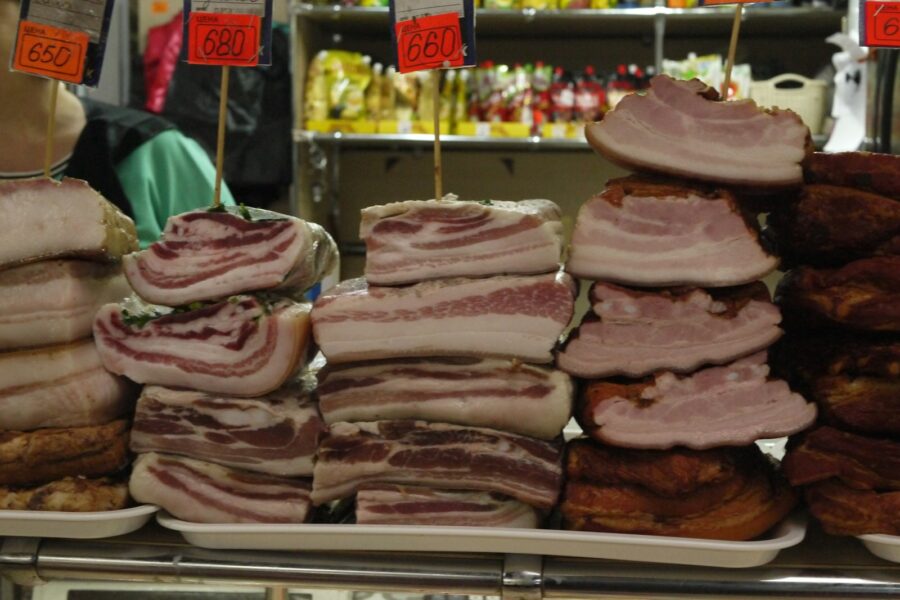 Stacks of cured meat and bacon at a market.