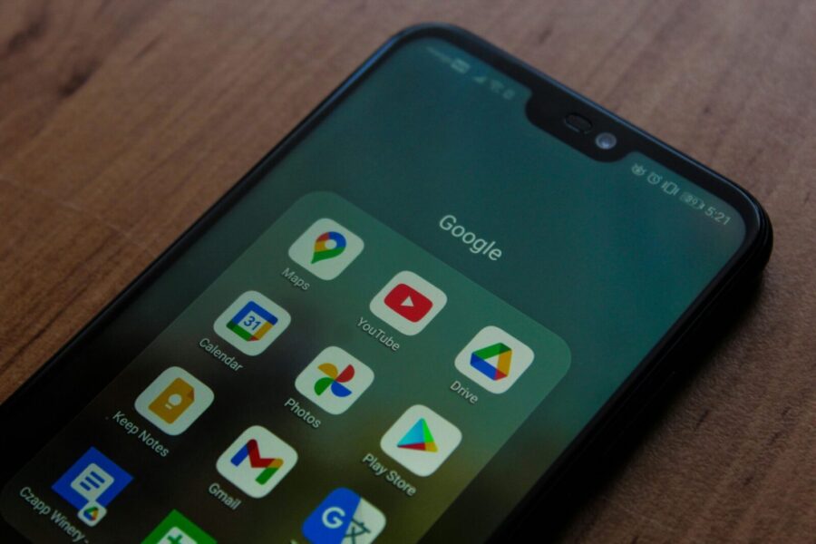 Close-up of a smartphone showing various Google apps on its screen.