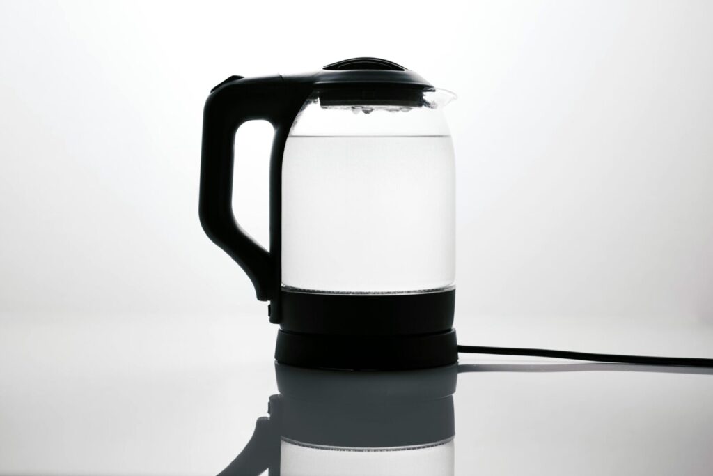 Sleek glass electric kettle with water, reflecting on a glossy surface, ideal for modern kitchens.