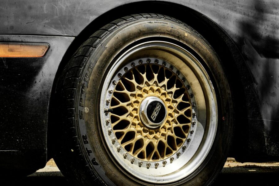 Detailed view of a black car's wheel showcasing intricate gold rim design.