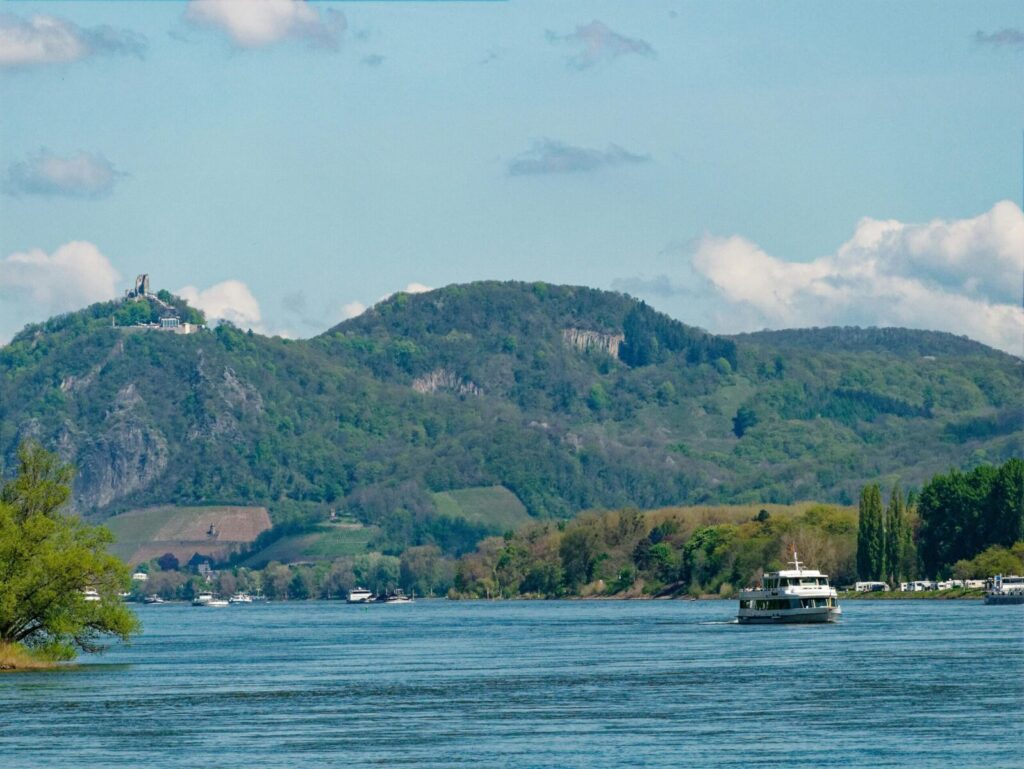 A picturesque view of the Rhine River with lush hills and sailboats in Unkel, Germany.