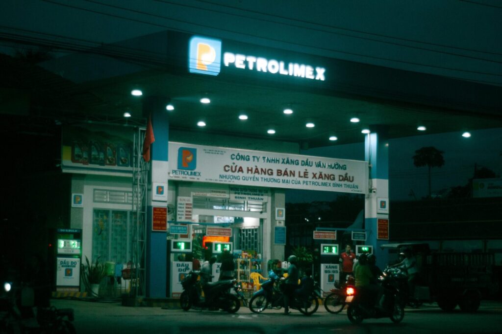 Motorcycles at a Petrolimex gas station in Vietnam at night with vibrant lighting.