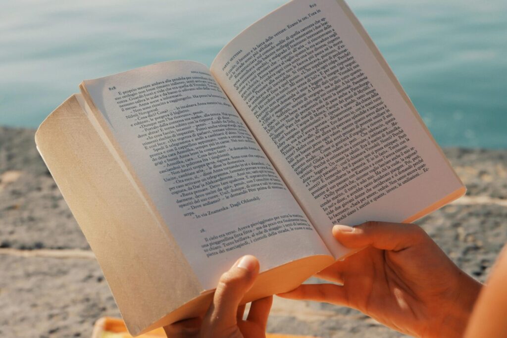 A person enjoys reading a book by the seaside in Syracuse, Sicily.
