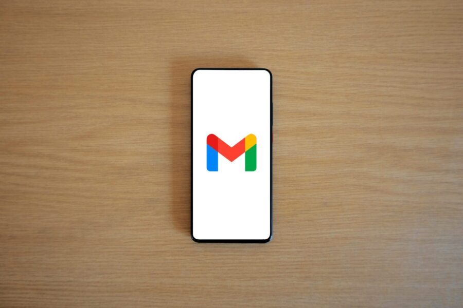 A smartphone displaying the Gmail app logo on a wooden surface, viewed from above.