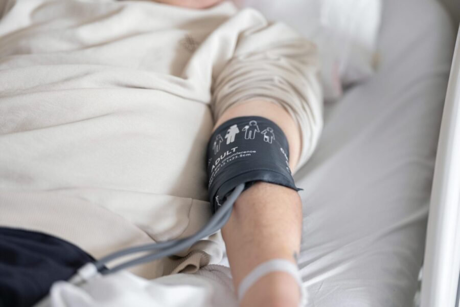 Close-up of patient in hospital bed with blood pressure cuff on arm, emphasizing healthcare theme.