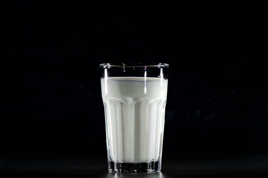 A glass of fresh milk against a black background, emphasizing simplicity and nutrition.