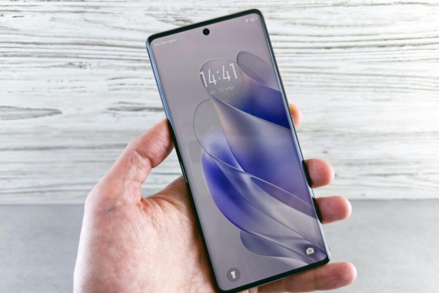 A detailed close-up of a hand holding a smartphone indoors, showcasing the screen in precise detail.